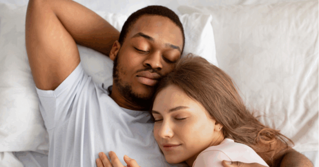Copy of Blog Featured Image Template A young couple lying in bed together, looking relaxed but slightly distant, symbolizing the challenges of intimacy and connection while breastfeeding.